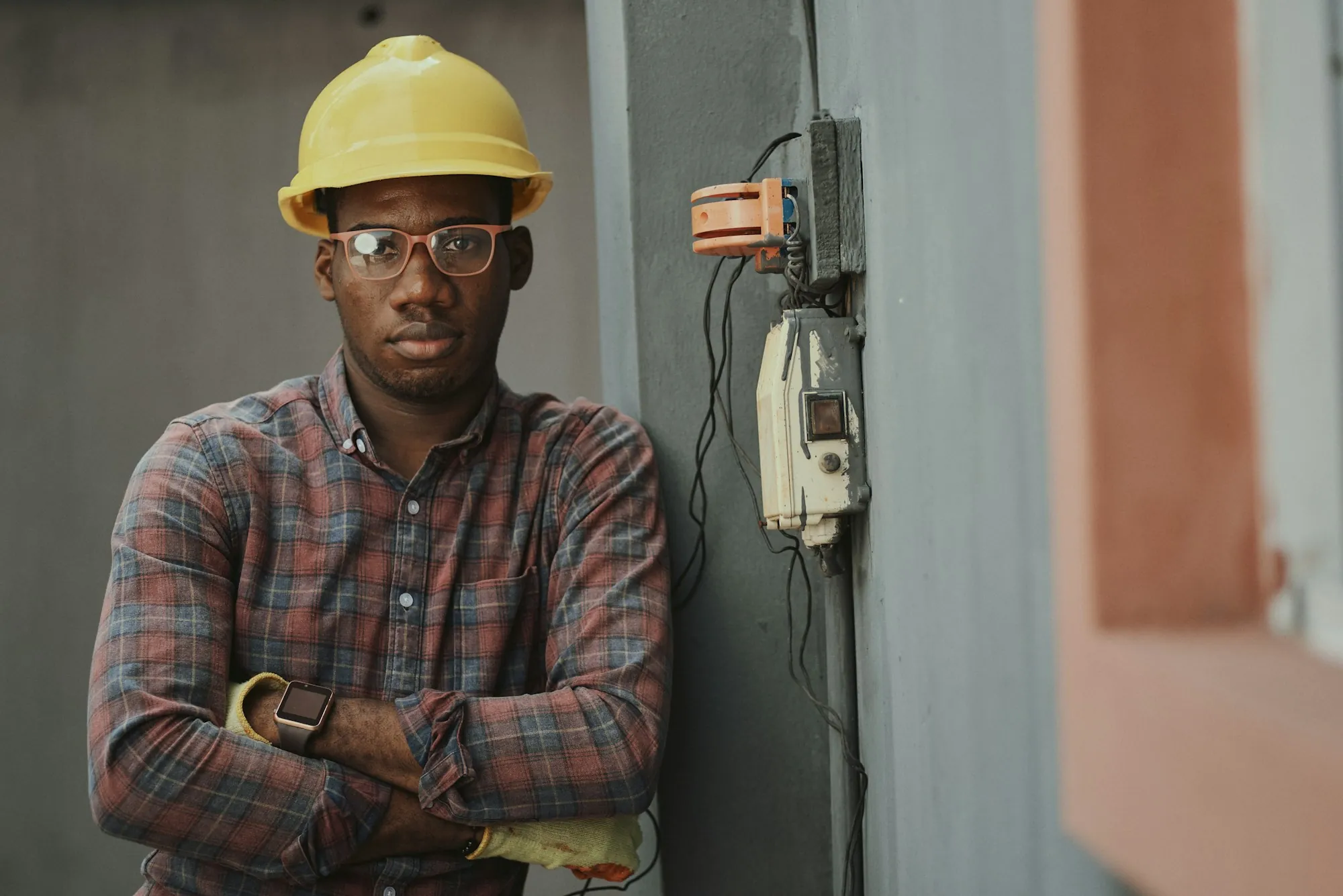 An electrician standing beside an exterior electrical enclosure