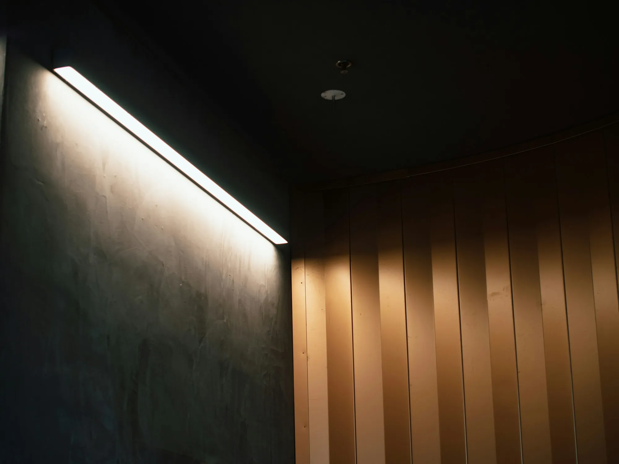 A linear light fixture casting soft light along a wall