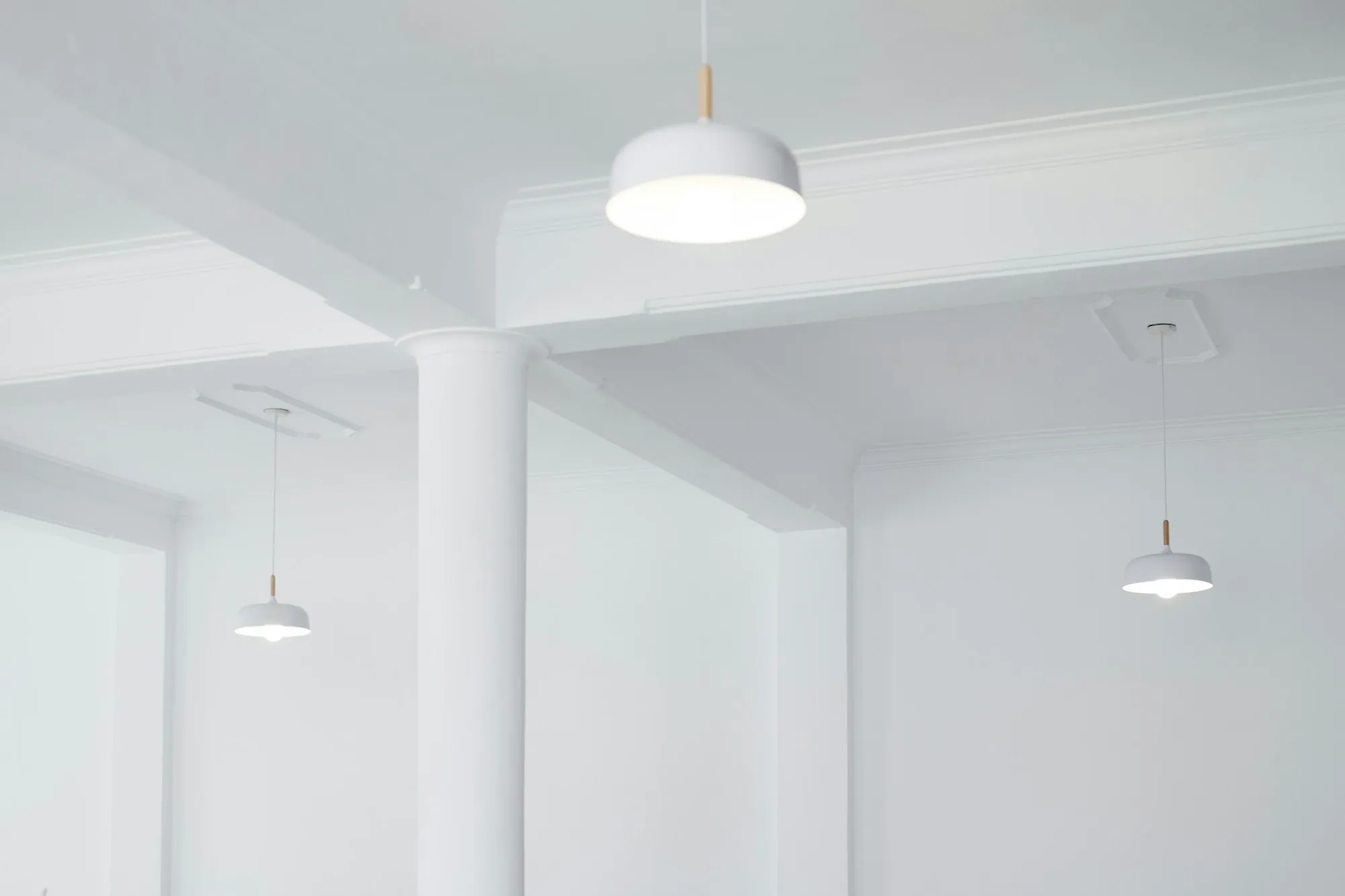 White pendant lamps hanging from a bright white ceiling